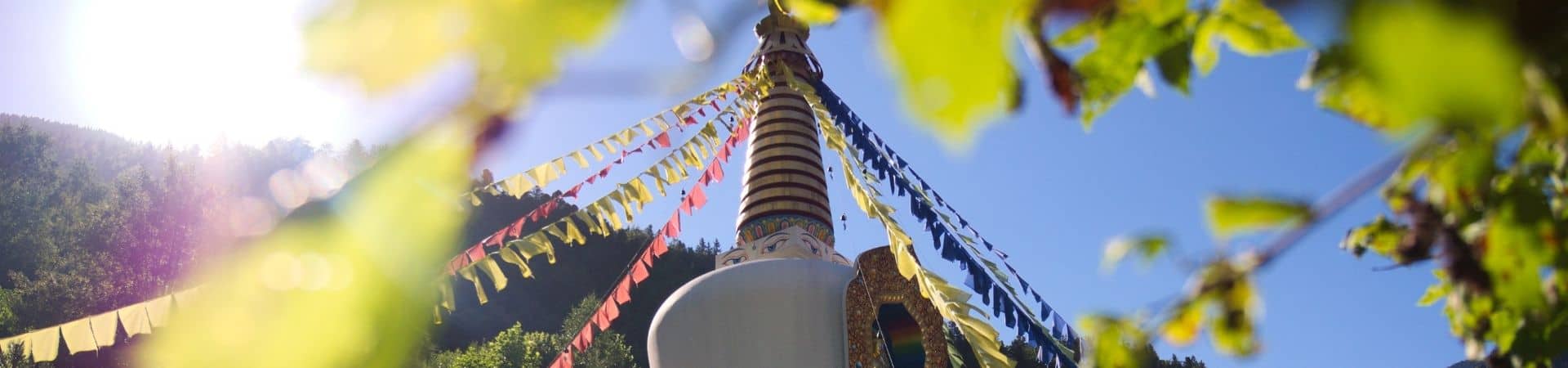 Stupa bouddhiste orné de drapeaux de prières colorés sous le soleil d'été, au centre de retraite Karma Ling en Savoie