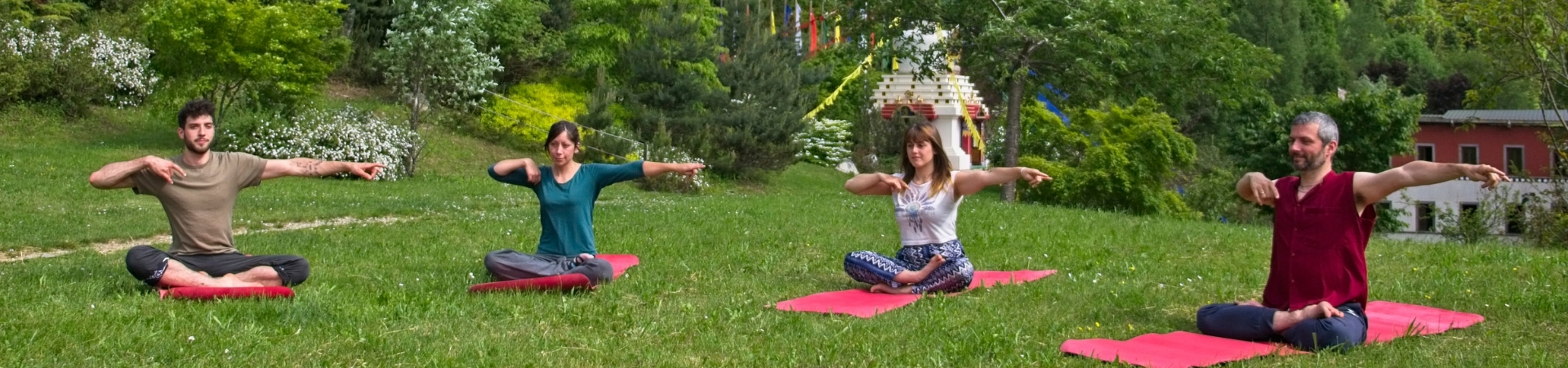 Quatre pratiquants en posture assise sur tapis rouges dans le jardin de Nigu Karma Ling, pratique du Yoga intérieur Nangpé Yoga